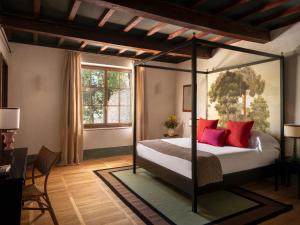 a bedroom with a canopy bed with red pillows at Fattoria di Vegi in Castellina in Chianti +86 photos