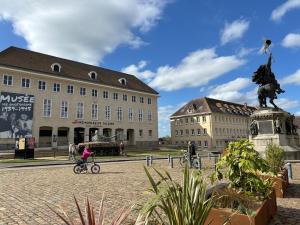 a girl riding a bike in front of a building at La clé du Temps in Falaise
