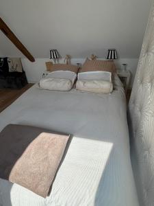 a large white bed with two pillows on it at La clé du Temps in Falaise