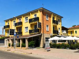 ein gelbes Gebäude mit weißen Sonnenschirmen davor in der Unterkunft Hotel Genesis in Vignola