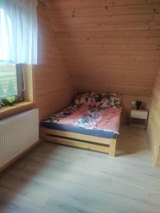 a small bed in a wooden room with a window at Dom letniskowy Krzyś in Przejma Wielka