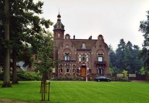a large brick building with a clock tower on top at De Vechthoeve in Dalfsen