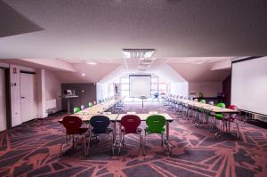 uma grande sala com mesas e cadeiras e uma tela de projeção em ibis styles Brive Ouest em Brive-la-Gaillarde