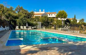 a swimming pool with blue water in front of a house at El Museo in Laroya