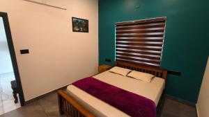 a small bed in a room with a green wall at Rambos Inn Homestay in Vagamon