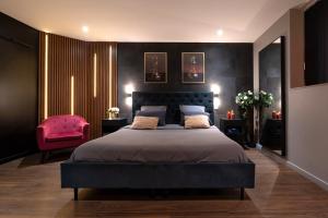 a bedroom with a large bed and a pink chair at Love Room Lorient - Le King Size - Balnéo 2 places in Lorient