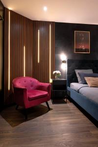 a bedroom with a pink chair and a bed at Love Room Lorient - Le King Size - Balnéo 2 places in Lorient +39 photos