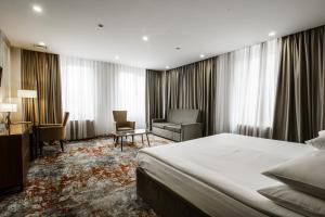 a hotel room with a bed and a chair at Dostyk Mildom Almaty in Almaty