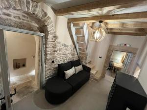 a living room with a black couch and a stone wall at Patossa in Chios