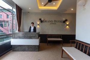 a man standing behind a counter in a hotel room at Grand Hotel Annex in Āīzawl