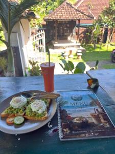 a plate of food with eggs and a book on a table at Family Hostel Lovina in Lovina