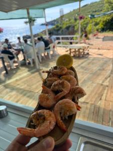 a person holding a piece of shrimp on a board at Camping Aquariumm in Himare