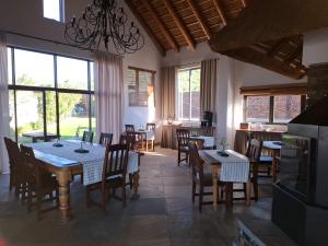 a dining room with tables and chairs and windows at 19th Hole Golf Villa Guesthouse in Worcester