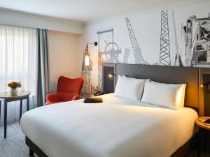 a hotel room with a large bed and a chair at Mercure Cardiff in Cardiff +119 photos