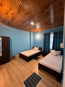 two beds in a room with blue walls and wooden ceilings at Home away homestay in Namchi
