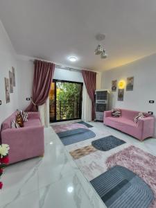 a living room with two pink couches and a large window at Ali Guest House in Jazīrat al ‘Awwāmīyah