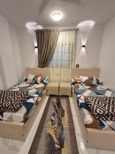 a room with three beds and a window at Ali Guest House in Jazīrat al ‘Awwāmīyah