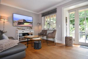 a living room with a couch and a tv on the wall at Gartenweg 9, Whg Oland in Tinnum