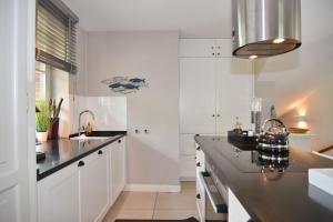 a kitchen with white cabinets and a black counter top at Gartenweg 9, Whg Oland in Tinnum +15 photos