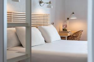 a bedroom with a bed with white pillows and a desk at Sercotel Puerto de Santa María in El Puerto de Santa María
