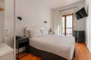 a bedroom with a large white bed and a window at Sercotel Puerto de Santa María in El Puerto de Santa María