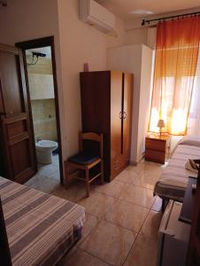 a room with two beds and a chair and a bathroom at L'Aragosta Guesthouse in Alghero