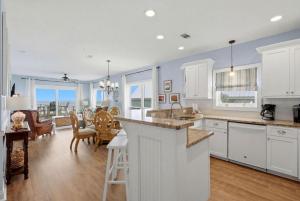 a kitchen with white cabinets and a dining room with a table at Riviera Dunes 203 in Perdido Key