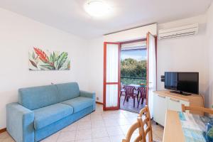 a living room with a blue couch and a television at Villa La Cavaliera in San Vincenzo