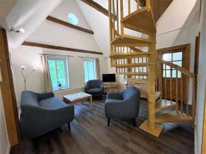a living room with two chairs and a spiral staircase at Hof Döttgebüll in Aventoft