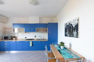 a kitchen with blue cabinets and a table with chairs at Villa La Cavaliera in San Vincenzo