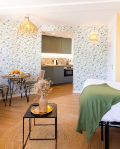 a bedroom with a bed and a table and a kitchen at Appart'Hôtel & Spa "Les Voiles" Le Groix in Carnac