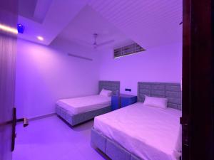 two beds in a room with purple lighting at Hotel Moon Light in Dhaka