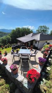 a patio with a table and chairs and flowers at Vujanac vikend kuća in Raška