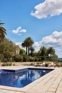 a swimming pool with palm trees in the background at Mas Palou in Pla del Panadés