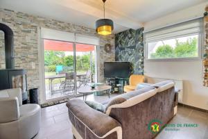 a living room with a couch and a tv at Les flots du bono in Le Bono