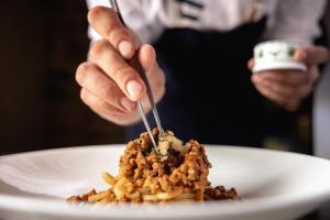 a person eating food on a plate with a fork and knife at Fattoria di Vegi in Castellina in Chianti