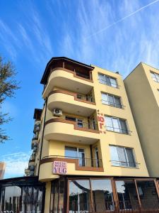 a tall yellow building with a sign in front of it at Хотел ЮГ in Primorsko