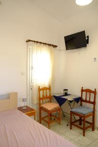 a bedroom with two chairs and a table and a tv at Small farmhouse by M in Egina