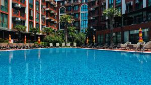 a large blue swimming pool with chairs and buildings at Chateau del Marina Apart Complex in Nesebar
