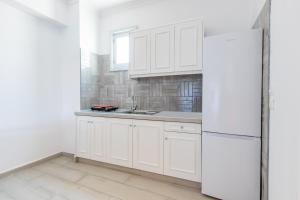 a kitchen with white cabinets and a white refrigerator at Zorbas Studios in Lefkos Karpathou +53 photos