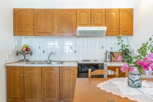 a kitchen with wooden cabinets and a table with pink flowers at Agnadi Apartment in Serifos Chora +23 photos