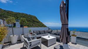 a patio with a couch and an umbrella at Villa Lilian by LovelyStay in Arco da Calheta