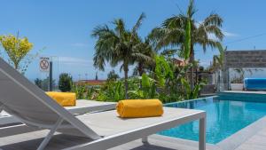 a pool with a lounge chair next to a swimming pool at Villa Lilian by LovelyStay in Arco da Calheta