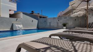 a swimming pool with chairs and a pool slide at Vila Agushi in Ksamil