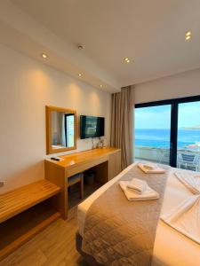 a hotel room with two beds and a desk and a window at Hotel Sole in Sarandë