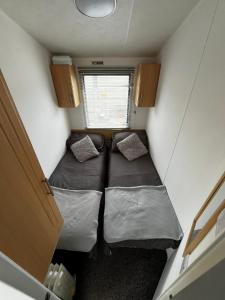 a small room with two beds and a window at Izabela's Caravan - Caravan 261 in Saint Osyth