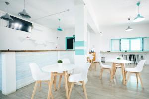 a dining room with white tables and white chairs at Hostal Sunset Ibiza in San Antonio