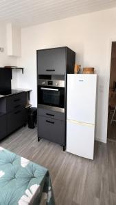 a living room with a refrigerator and a kitchen at Le Cocooning - 4 voyageurs - Jardin,Terrasse in Saint-Nazaire