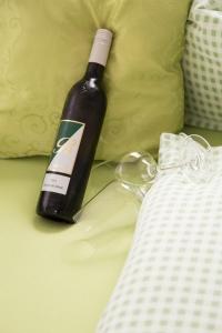 a bottle of wine sitting next to a bed at Obst- und Weinbauernhof BERNHARD in Leutschach