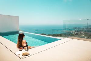 a woman sitting on the edge of a swimming pool at SIVOTA SUNSET VILLAS in Syvota
